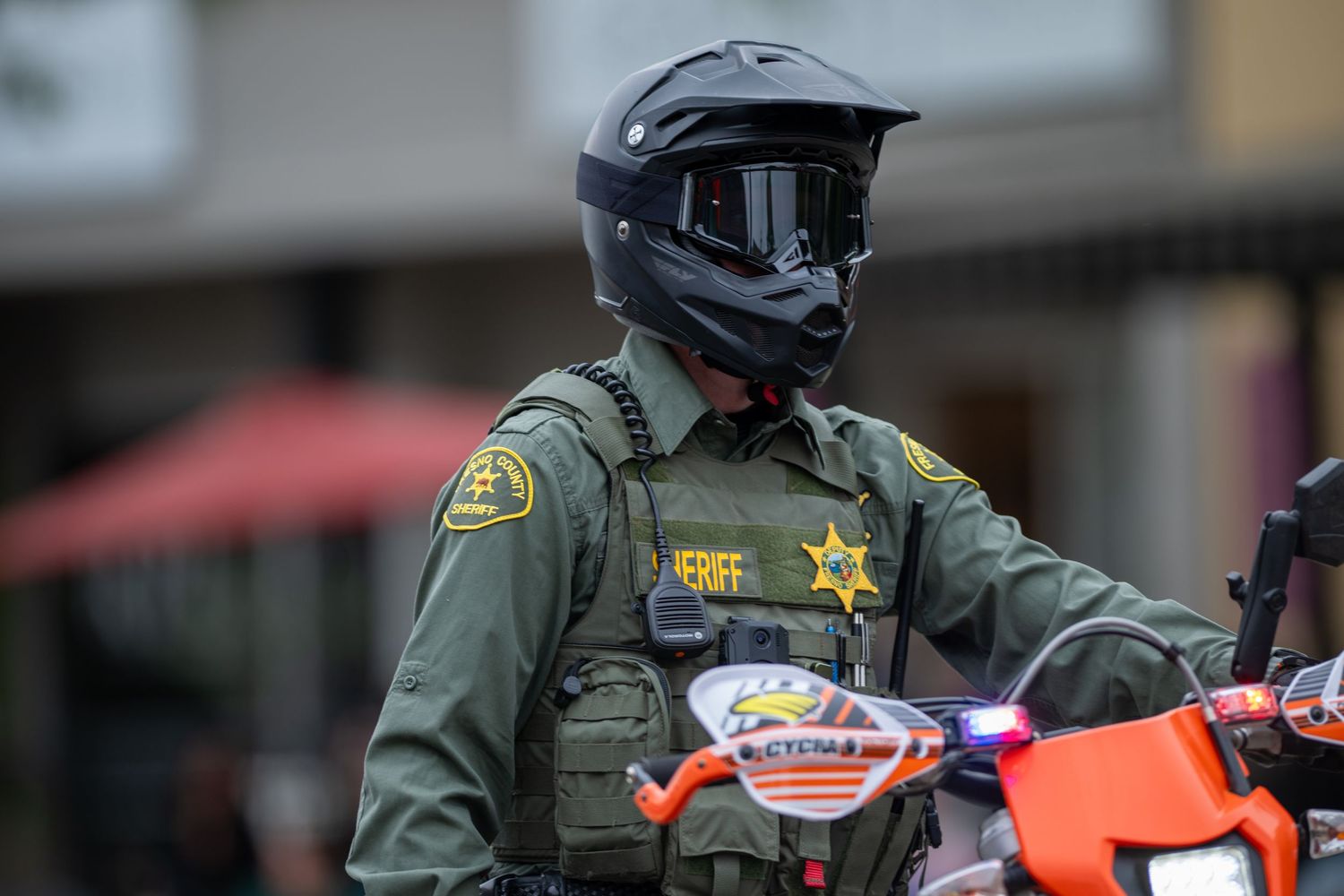 Sheriff deputy in protective gear on motorcycle at community event.