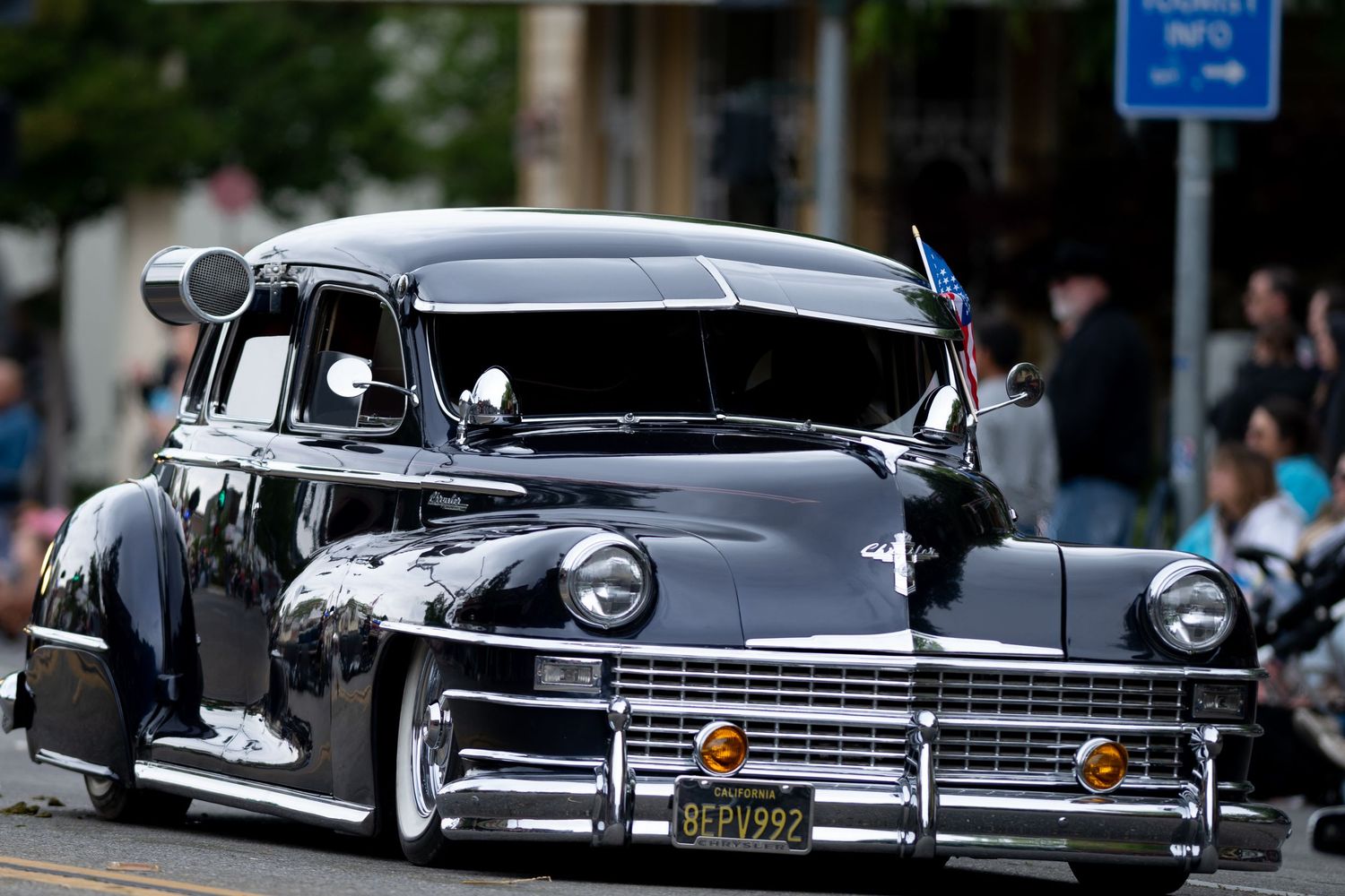 A custom lowered vintage Chrysler in metallic gray showcased at a car parade.