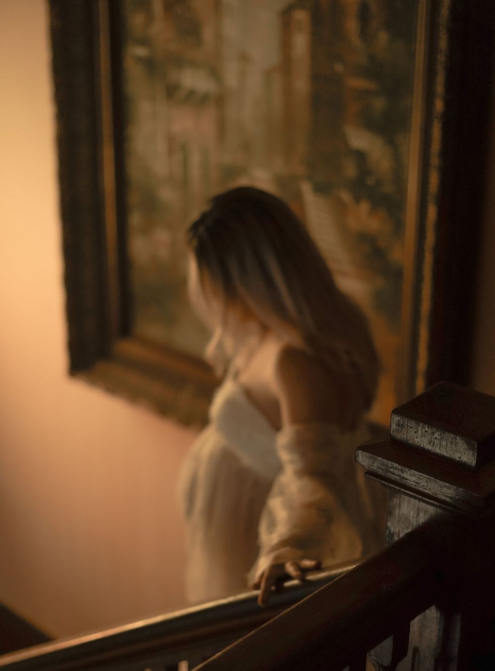 maternity session of a new mother to-be walking down the steps in a vintage house in a chic sheer dress showing off her beautiful belly