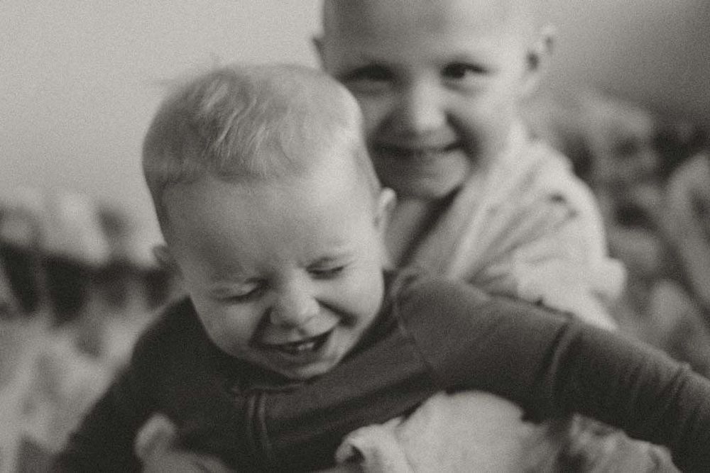 Vintage black and white photo of two young siblings laughing and playing together joyfully.