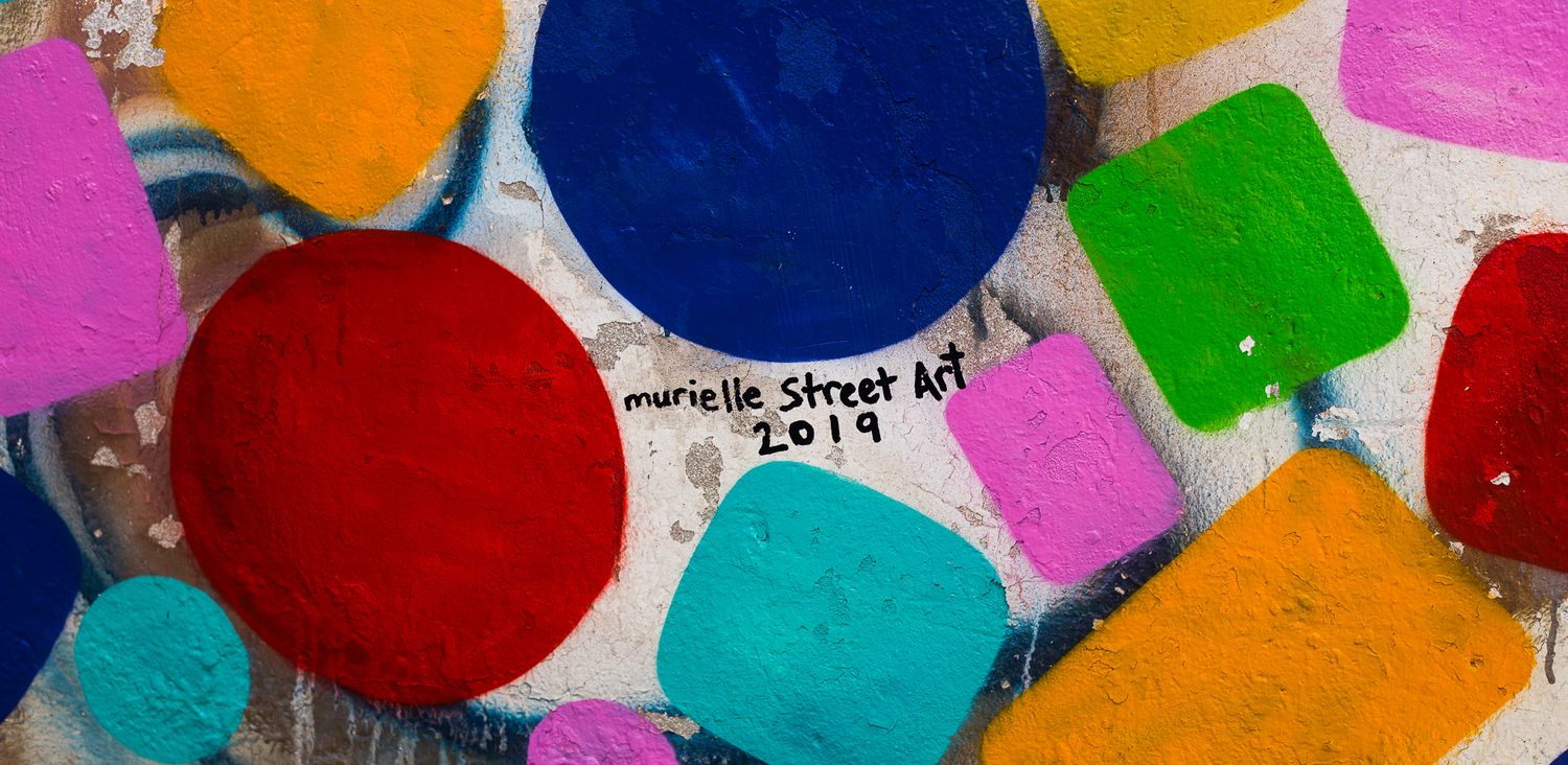 Vibrant colorful abstract street art mural with dots and geometric shapes painted on urban wall.