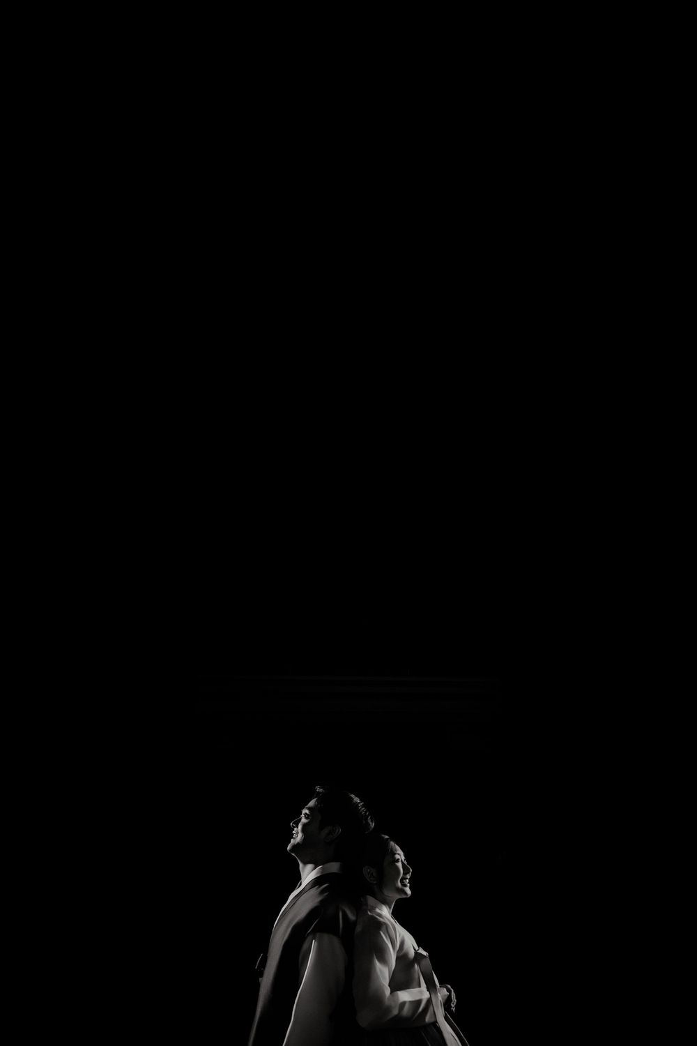 A dramatic silhouette shot against pure black background with high contrast lighting creates a striking profile.
