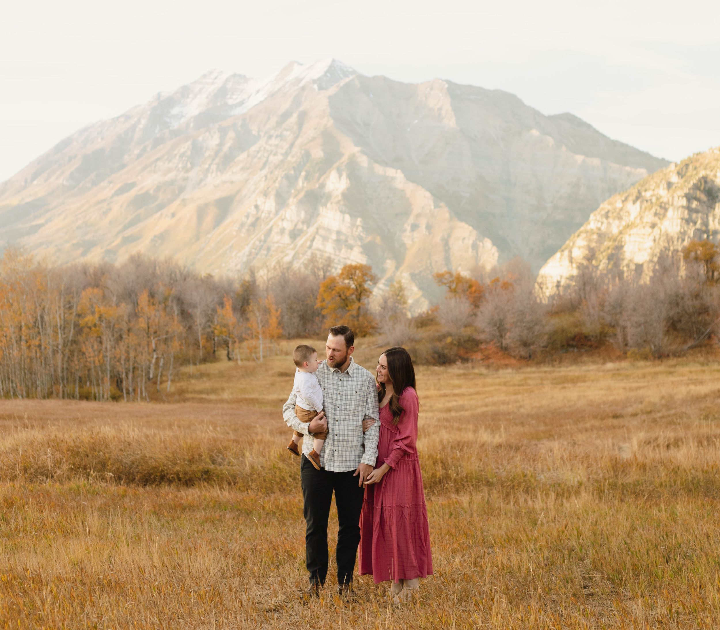 A couple shares an intimate moment in a field with majestic mountains in the background in Provo, Utah.