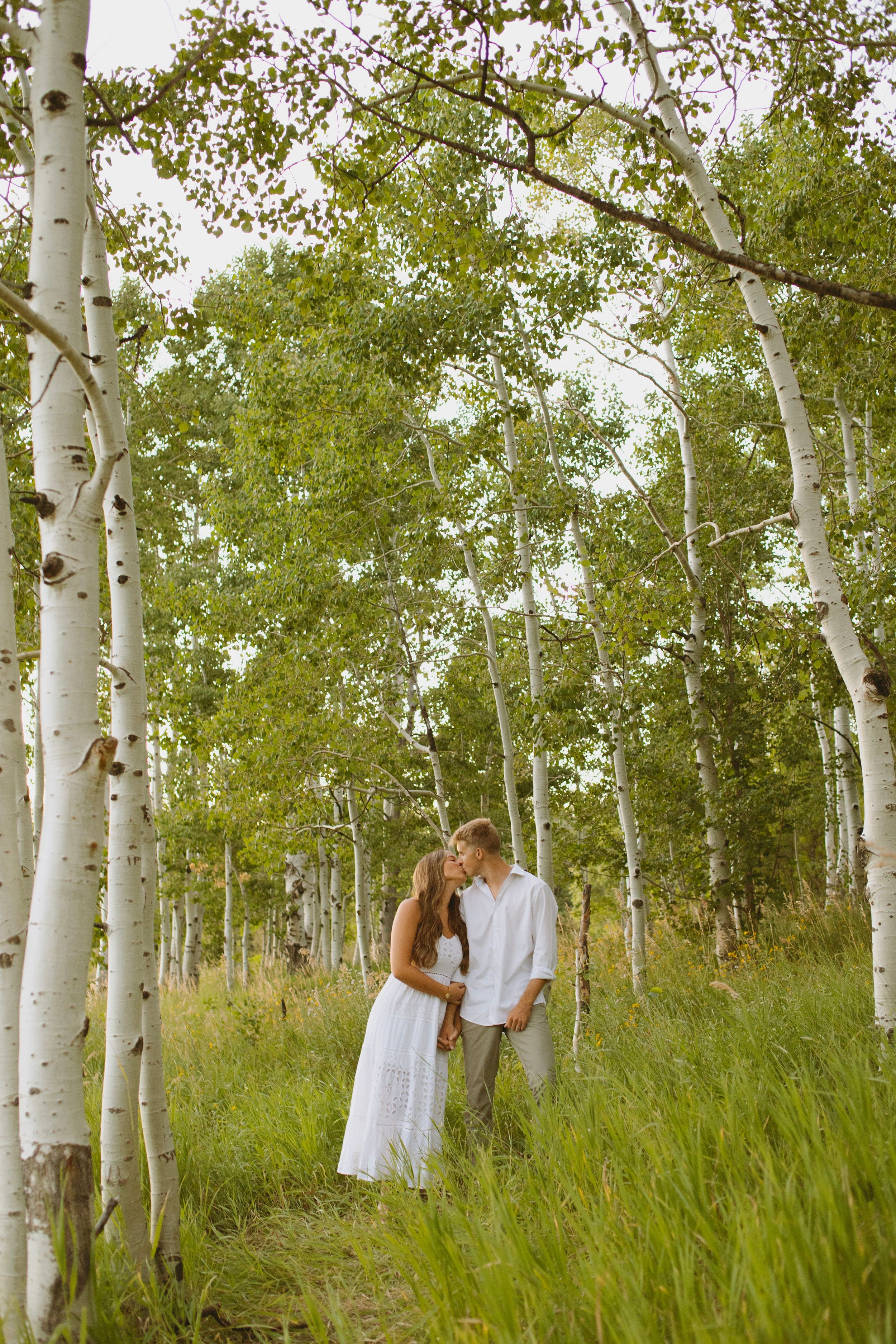 A romantic moment between a couple among tall aspen trees in a mountain meadow in Provo, Utah.