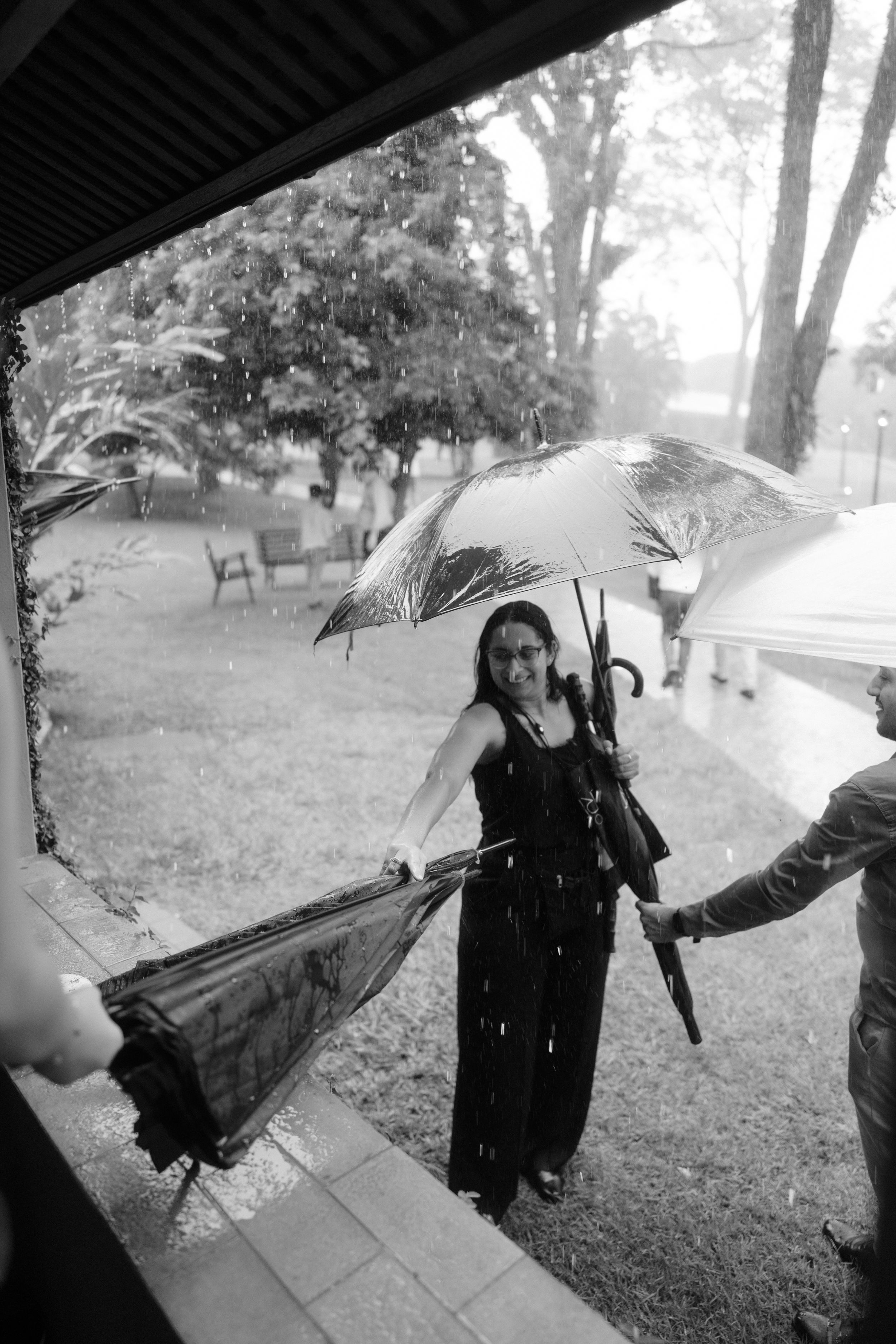 Sequence showing guests with umbrellas walking in the rain.