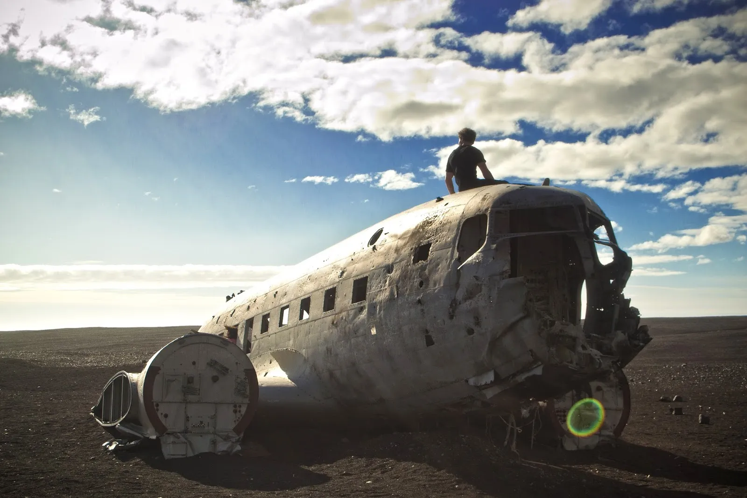 Épave d’un avion sur une plage en Islande, ciel dégagé en arrière-plan.