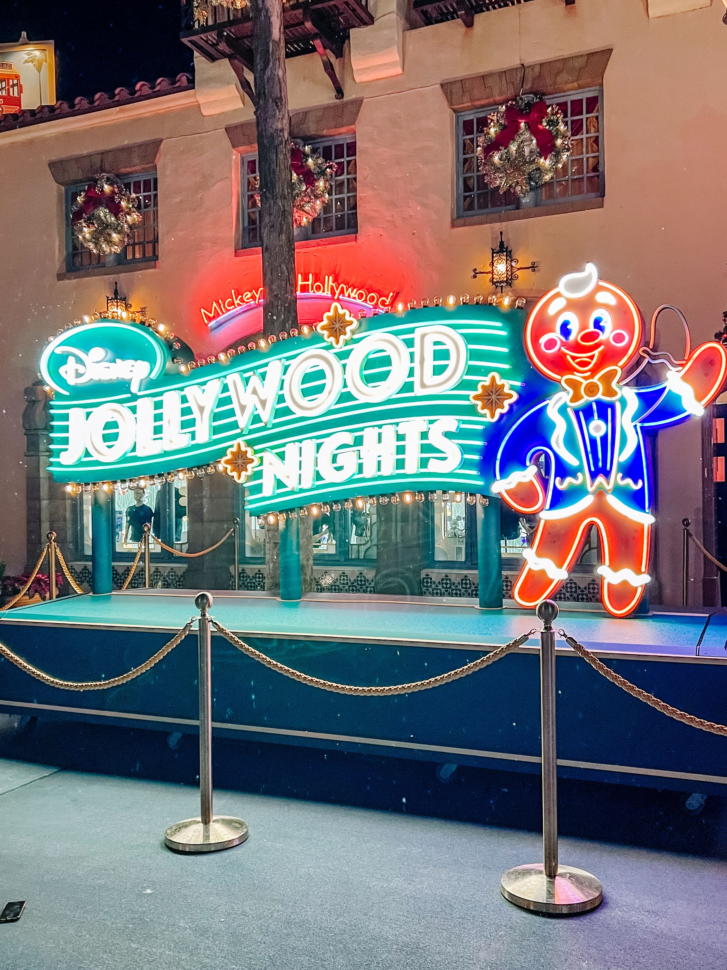 Illuminated Hollywood-themed neon signs glowing in blue and green against a dark background.