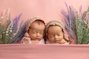 A professional newborn photography setup with soft natural light and lavender flowers arranged in the background.