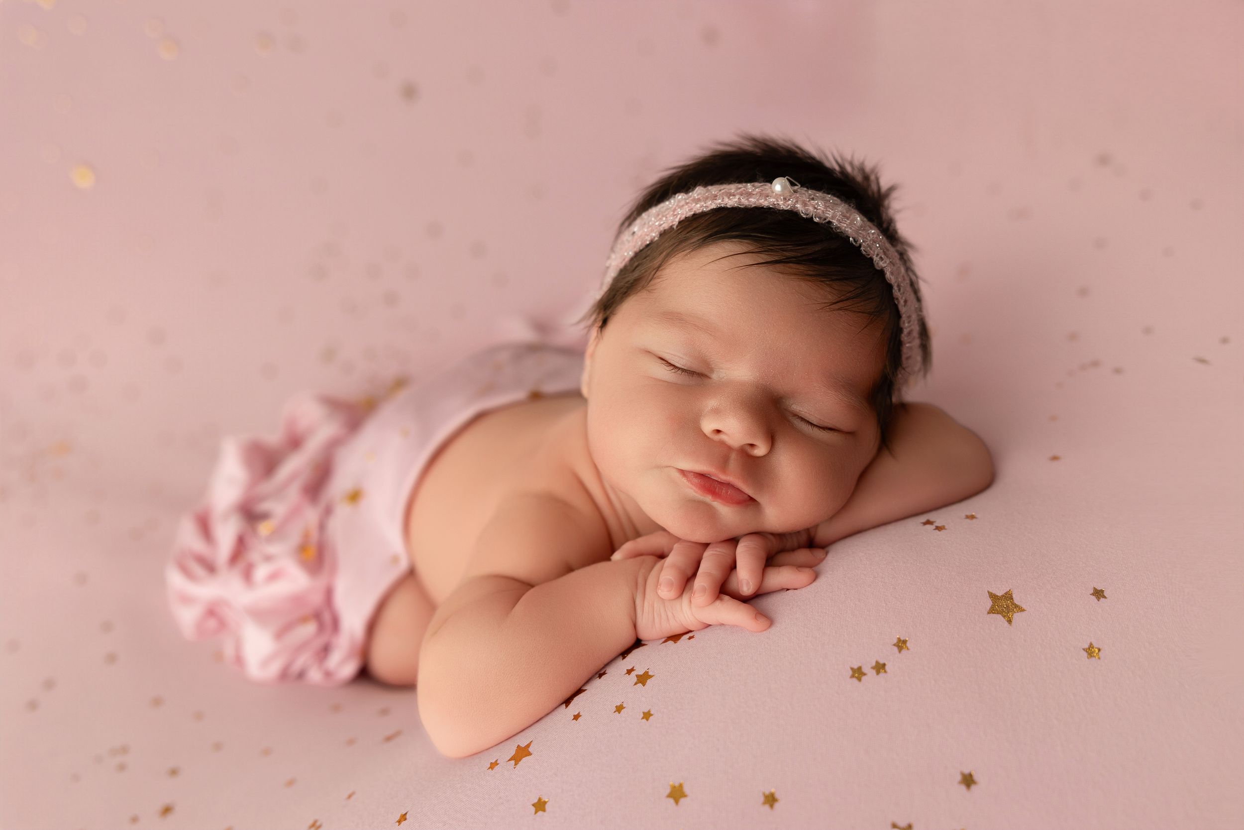 Sleeping newborn baby posed in pink and gold themed artistic collage with multiple angles.