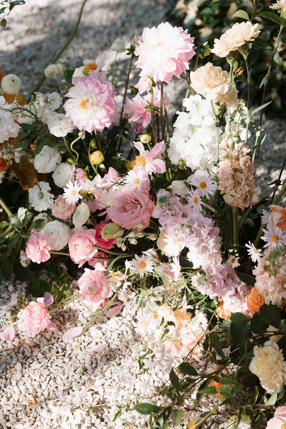 Delicate pink and cream garden roses and flowers arranged in a romantic vintage-inspired floral display against stone.