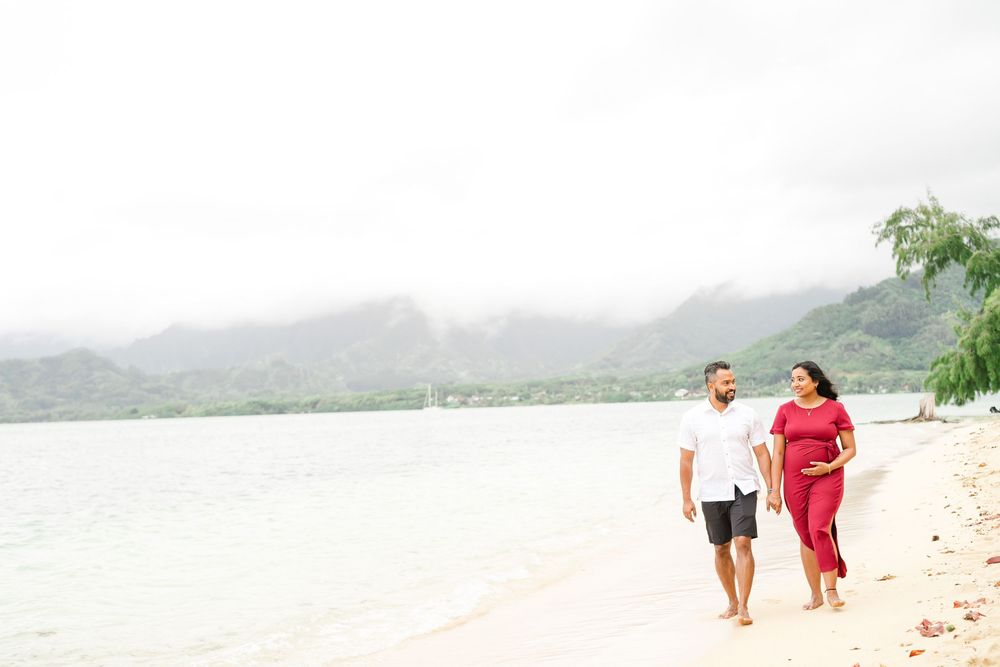 Two people stroll together along a misty tropical beach with mountains in the background.　Oahu Family Photographer | Aya S Tomikawa Photogra