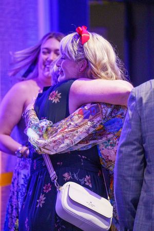 Two people enjoy a night out wearing floral prints and sparkly decorations under purple lighting at an event.