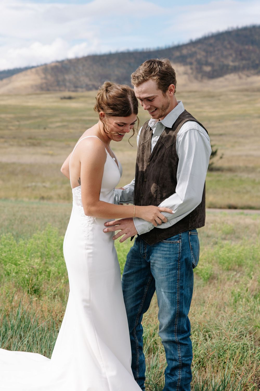 An intimate moment between newlyweds in a rustic country setting with mountains in the distance.