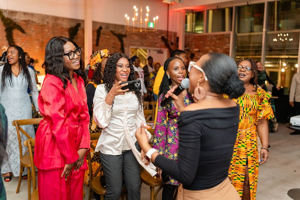 A group of people dancing and celebrating at an indoor event with brick walls and warm lighting.