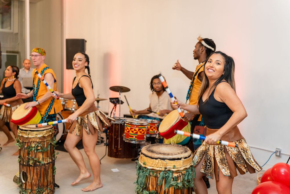 Performers in grass skirts play traditional drums during a vibrant cultural dance performance.