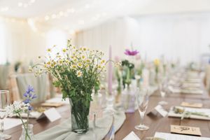 Table setting with wildflower centerpiece and wine glasses at wedding reception.