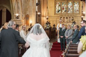 Wedding ceremony in progress inside a historic church with stained glass windows and vaulted ceilings.