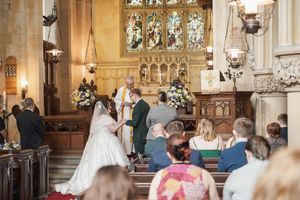 Beautiful church wedding ceremony with guests seated in wooden pews and floral decorations.