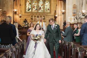 A wedding ceremony taking place in a traditional church with stained glass windows and wooden pews.