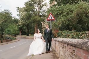 Newlyweds walking together along stone wall on quiet country road.