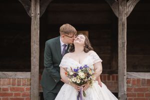 A romantic wedding portrait captured under a rustic wooden shelter.