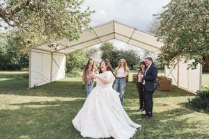 A wedding celebration scene under a white tent canopy in a garden setting.