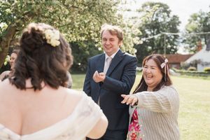 Wedding guests share a laugh during outdoor garden celebration.