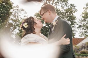 Intimate moment between newlyweds captured in soft focus with greenery in background.