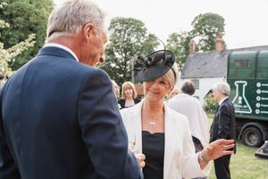 Wedding guests in formal attire conversing during an outdoor reception.