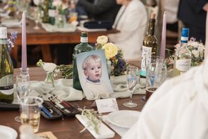 Wedding reception table decorated with photos, wine bottles and delicate floral arrangements.