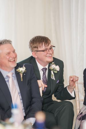 Joyful moment captured during wedding reception with elegant floral boutonnieres.