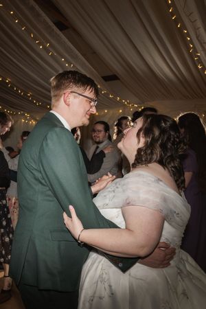 Couple share an intimate dance moment under twinkling fairy lights during their wedding reception.