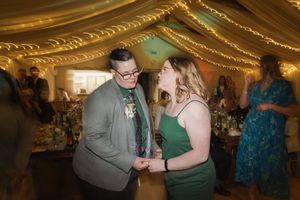 A candid moment captured at a wedding reception under warm golden lighting and string lights.