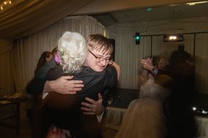 Guests embrace on a dimly lit dance floor during wedding celebration.