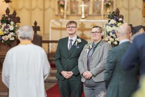 Traditional church ceremony with floral arrangements and attendees gathered at the altar.