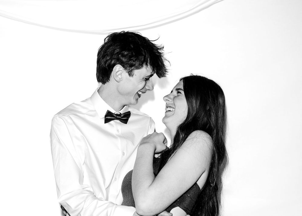 Black and white photo of a smiling couple in formal attire sharing an intimate moment together.
