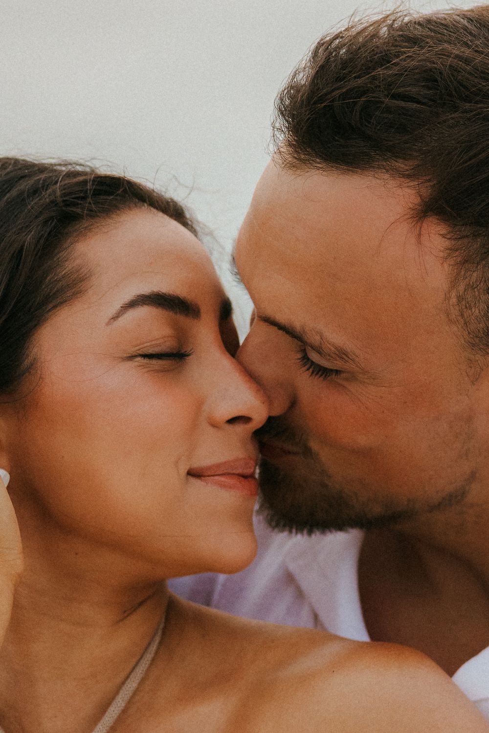 Close up of a romantic couple sharing an intimate moment with eyes closed in warm sunlight.