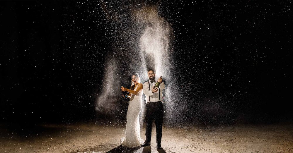 A couple stands in darkness as white powder or flour explodes around them creating a dramatic effect.