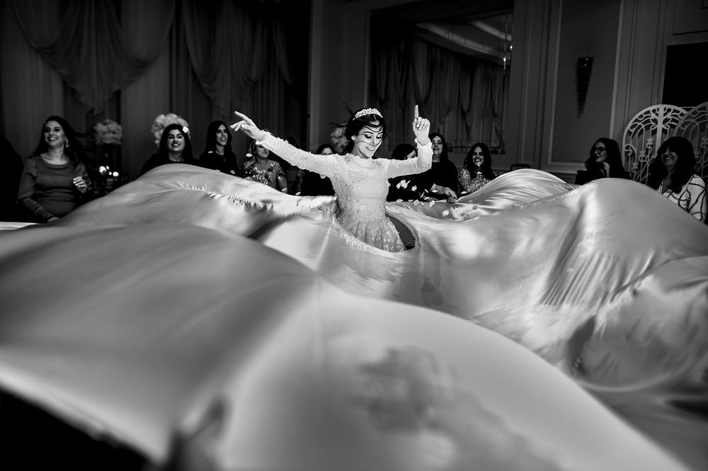 A dancer in white twirls gracefully as fabric billows around them during a performance.