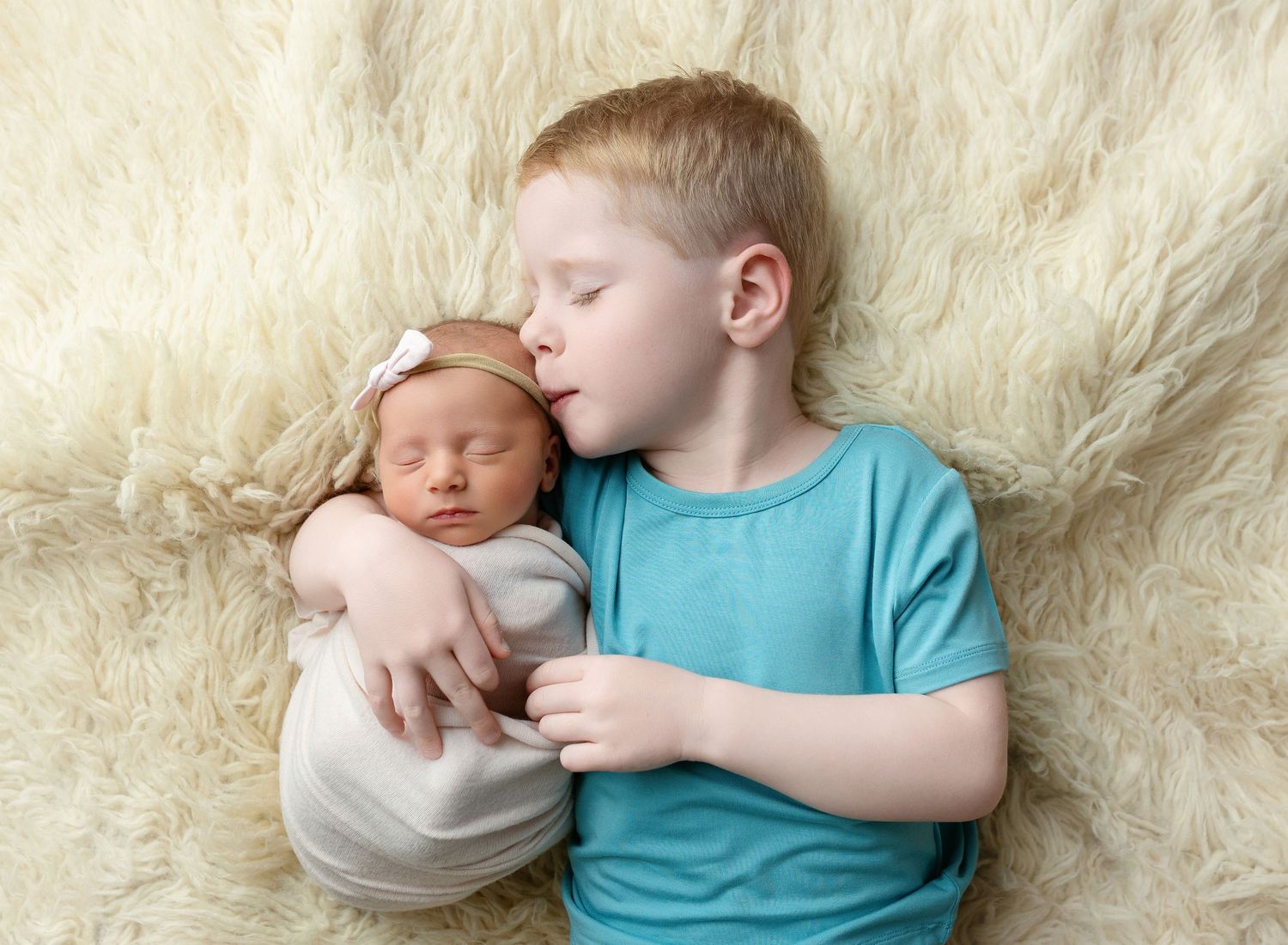 Big brother is holding newborn sister and kissing her. Greenville SC newborn photographer, Easley SC newborn photographer