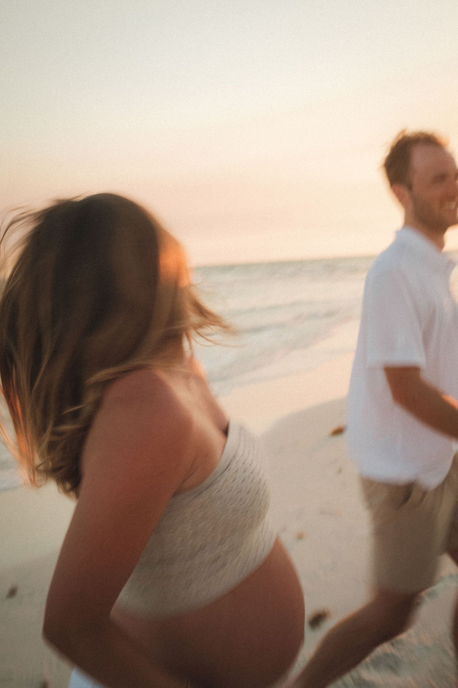Romantic couple shares intimate moments during sunset photoshoot on a sandy beach.