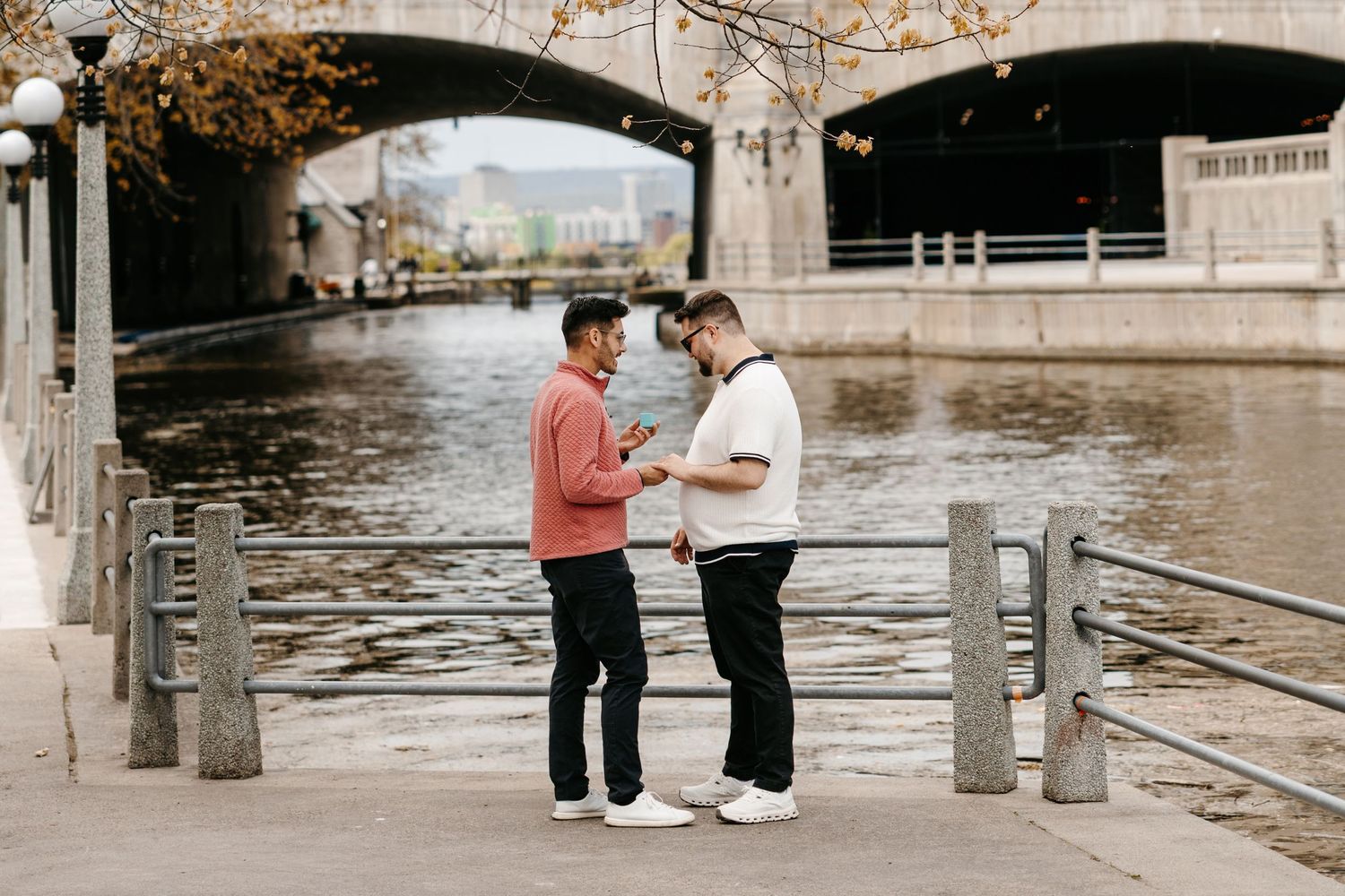 A scenic proposal moment between a couple near a fountain in a garden with water spraying in the background.