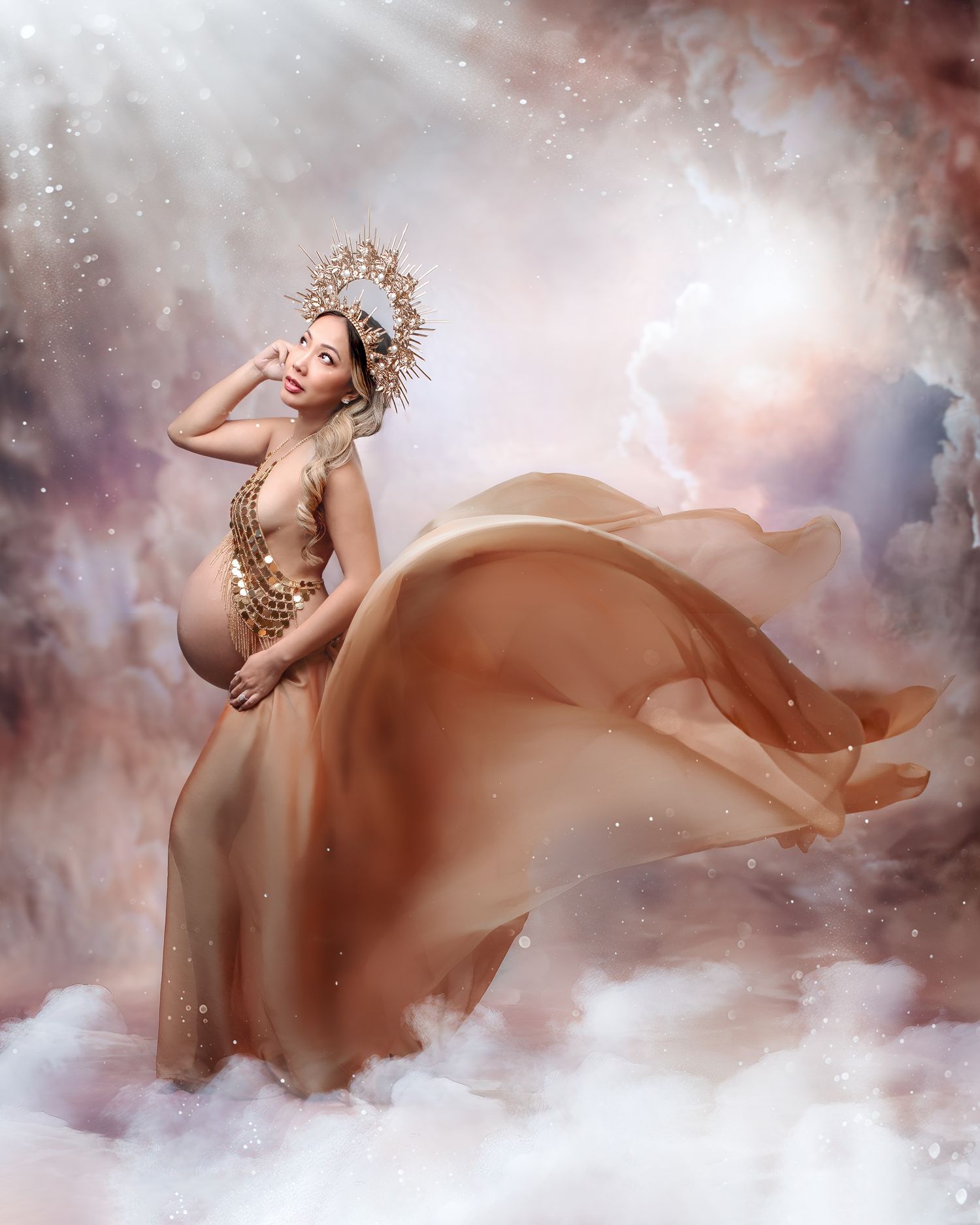 Expectant mother twirling in a voluminous gold chiffon tulle gown, movement captured in studio.