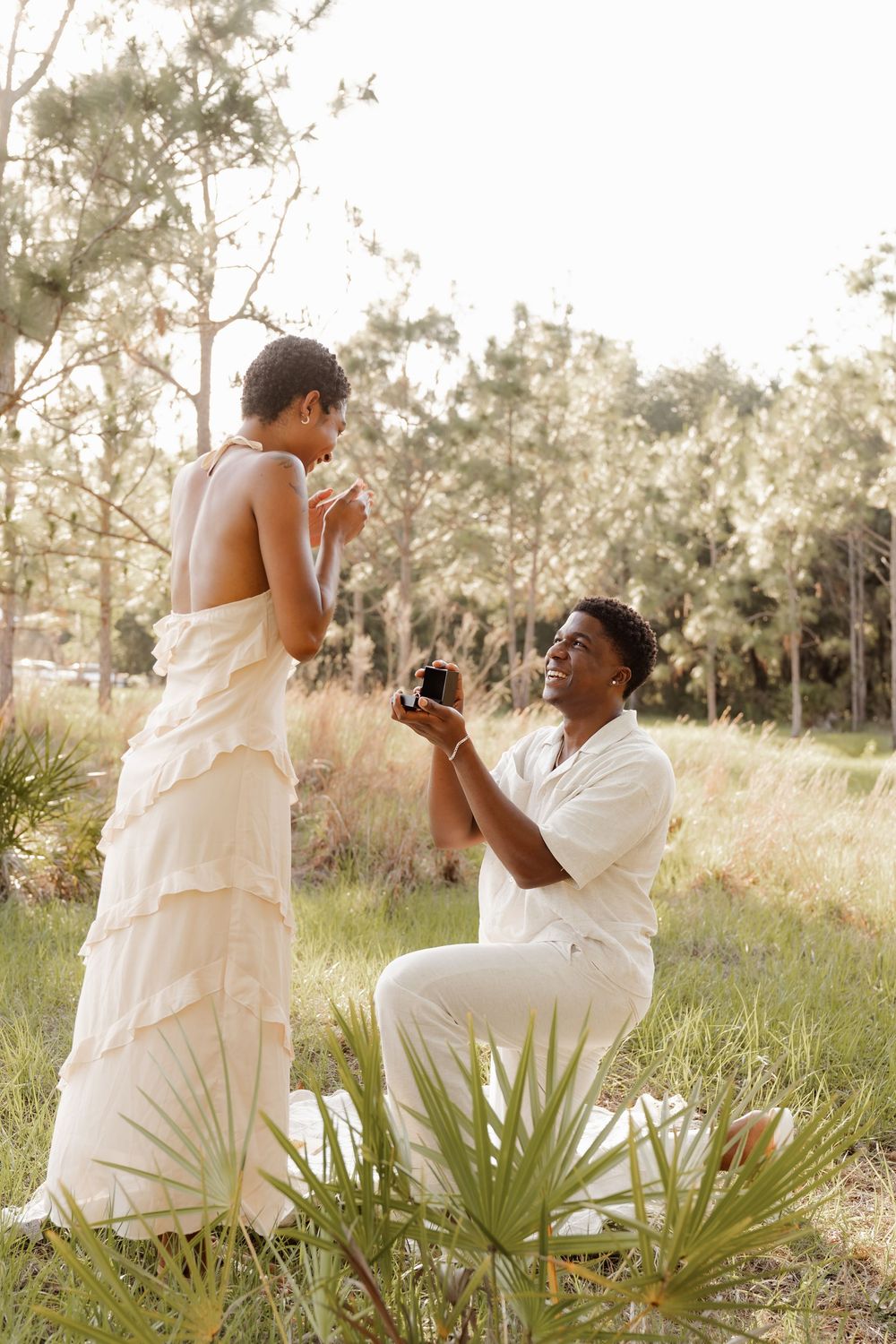 A romantic outdoor photo sequence showing a couple in white attire posing in a grassy field with palm plants at sunset.