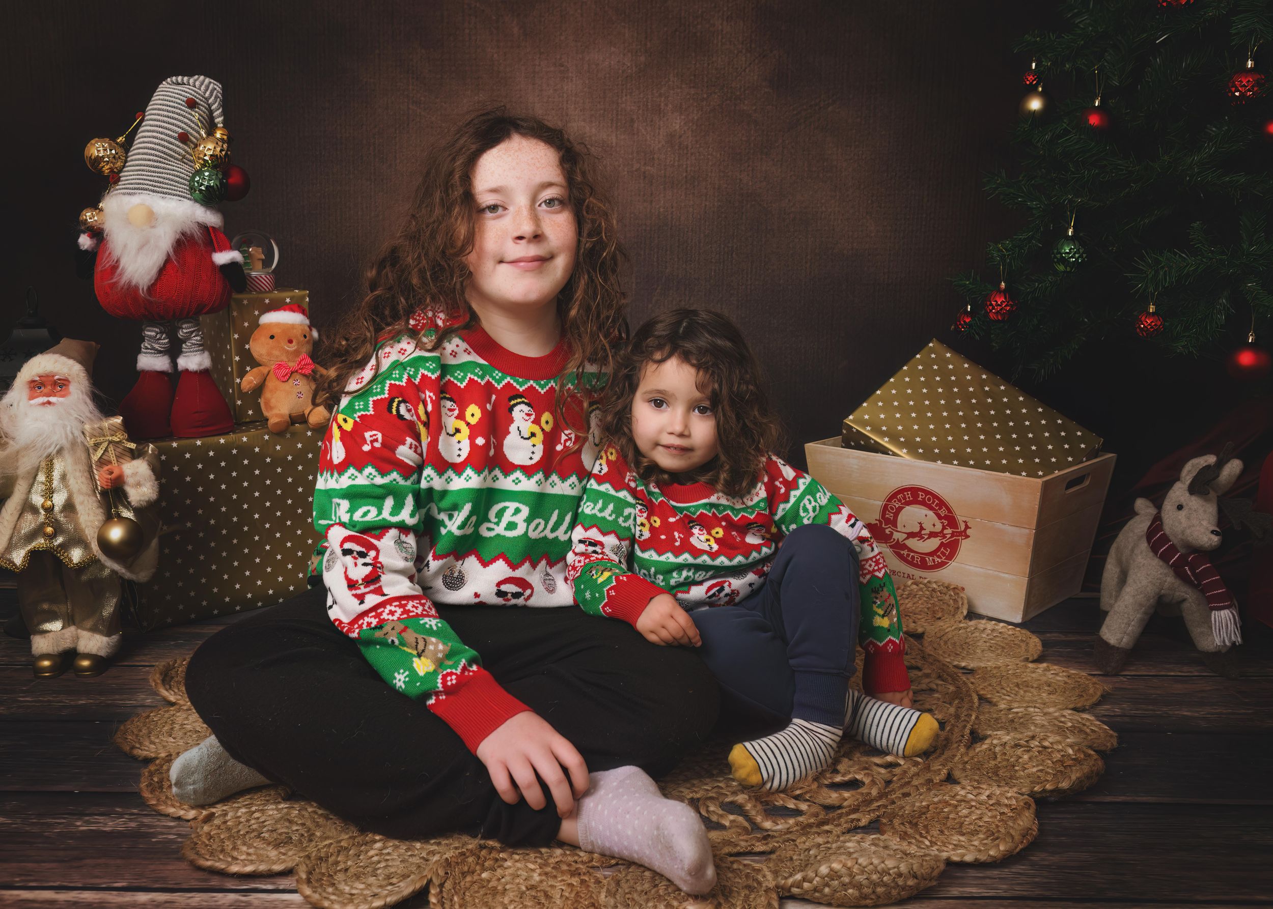 Christmas portrait of two sisters in ugly Christmas sweaters.