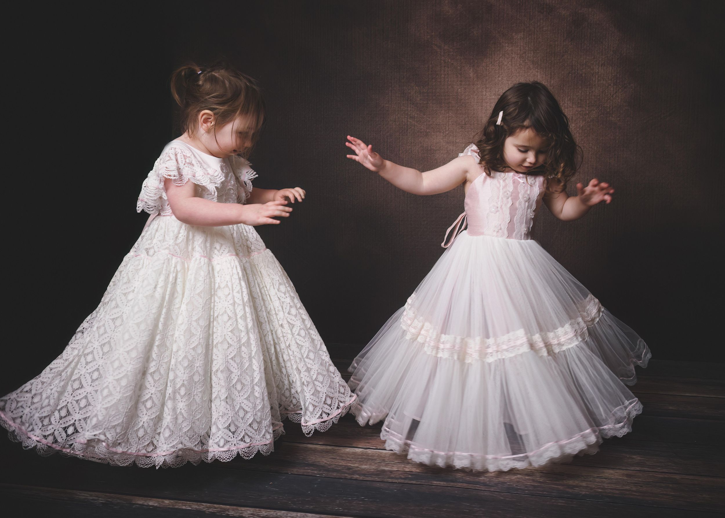 Two toddler girls in white Dollcake dresses dancing in painterly style.