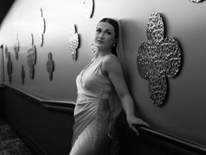 Wedding portrait in black and white with bride leaning against a wall covered in large metal flowers.