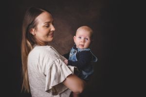 Mother and son portrait with baby looking towards the camera in painterly style.