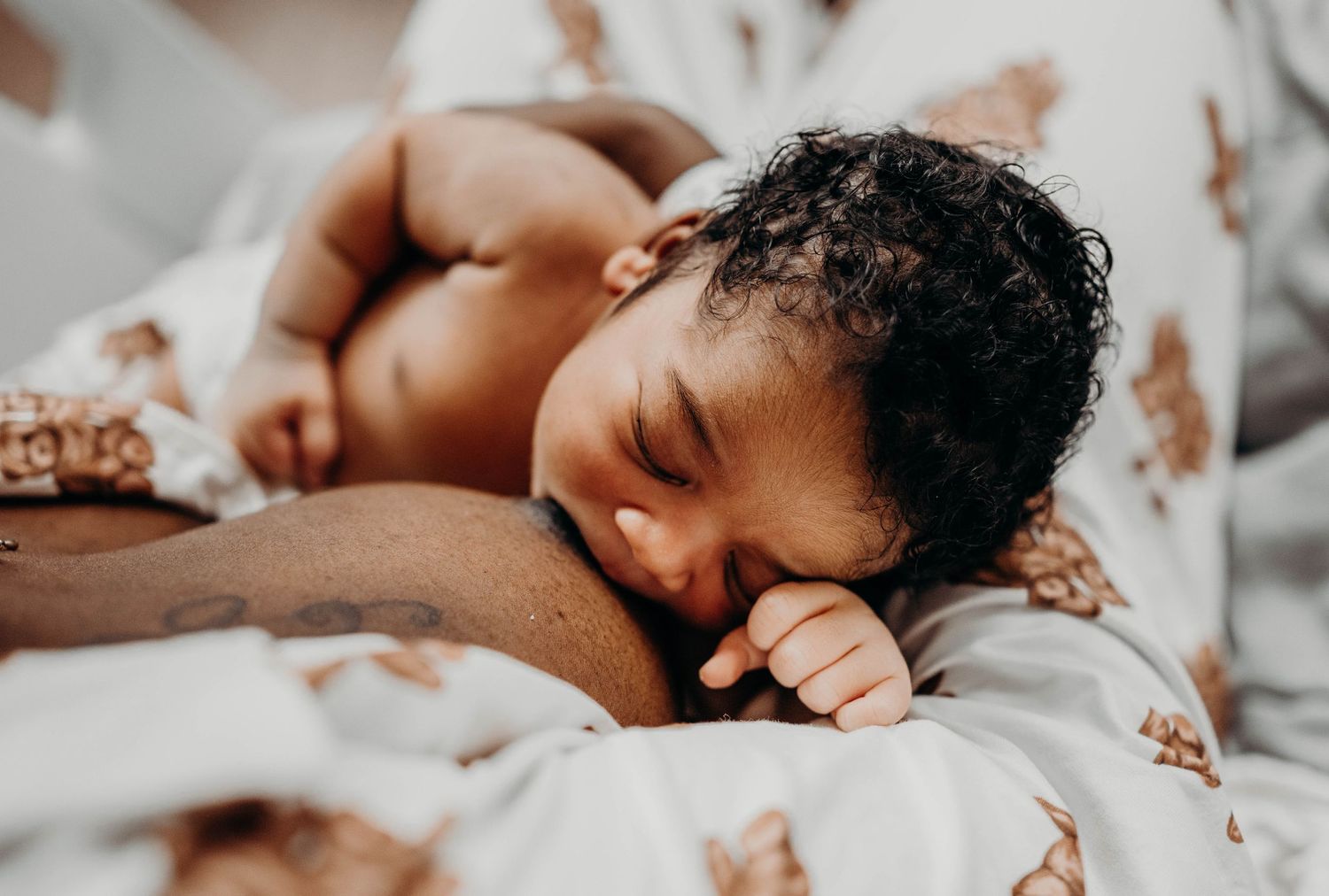 A peaceful sleeping baby with curly hair rests on soft bedding.
