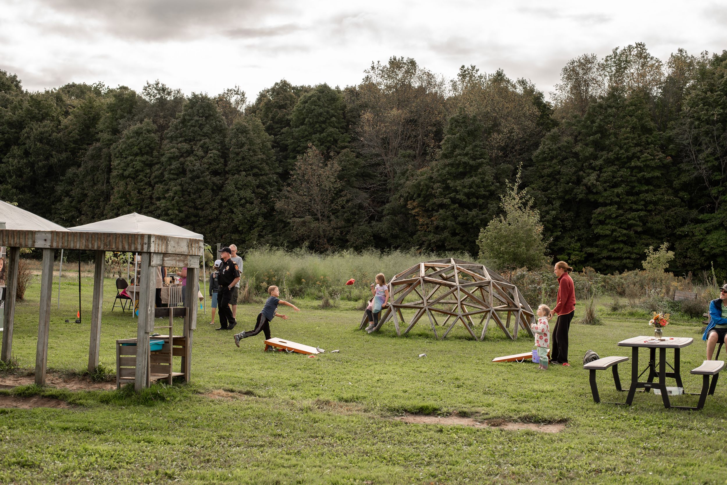 kids and adult tossing beanbag for cornhole game at farm market